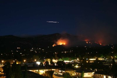 After all the lights and under the fire, near the foot of the hill.  The white line in the sky is a firefighting chopper coming in for a water drop.